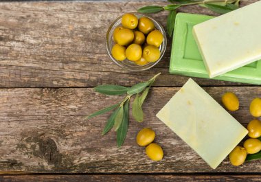 Kahverengi desenli ahşap üzerine zeytinyağı özlü doğal sabun. Yeşil, besleyici sabun ve zeytin çileği parçaları. Vücut bakımı ve spa konsepti. Metin için yer. Boşluğu kopyala. Düz konum