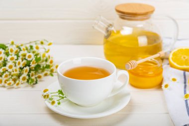 Arka planda taze papatya çiçekleri olan bitki çayı. Sakinleştirici ve rahatlatıcı bir içecek. Dokunulmazlık. Bir fincan sıcak papatya çayı. Çay içme konsepti. Çay seremonisi. Metin için yer, kopyalama alanı.