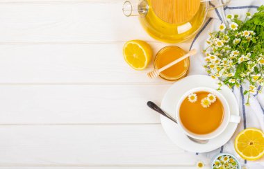 Arka planda taze papatya çiçekleri olan bitki çayı. Sakinleştirici ve rahatlatıcı bir içecek. Dokunulmazlık. Bir fincan sıcak papatya çayı. Çay içme konsepti. Çay seremonisi. Metin için yer, kopyalama alanı.