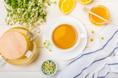 Arka planda taze papatya çiçekleri olan bitki çayı. Sakinleştirici ve rahatlatıcı bir içecek. Dokunulmazlık. Bir fincan sıcak papatya çayı. Çay içme konsepti. Çay seremonisi. Metin için yer, kopyalama alanı.