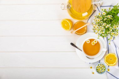 Arka planda taze papatya çiçekleri olan bitki çayı. Sakinleştirici ve rahatlatıcı bir içecek. Dokunulmazlık. Bir fincan sıcak papatya çayı. Çay içme konsepti. Çay seremonisi. Metin için yer, kopyalama alanı.