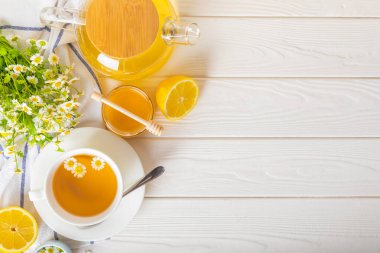 Arka planda taze papatya çiçekleri olan bitki çayı. Sakinleştirici ve rahatlatıcı bir içecek. Dokunulmazlık. Bir fincan sıcak papatya çayı. Çay içme konsepti. Çay seremonisi. Metin için yer, kopyalama alanı.