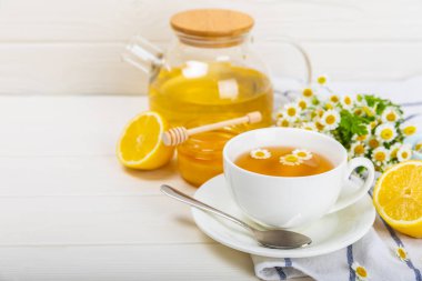 Arka planda taze papatya çiçekleri olan bitki çayı. Sakinleştirici ve rahatlatıcı bir içecek. Dokunulmazlık. Bir fincan sıcak papatya çayı. Çay içme konsepti. Çay seremonisi. Metin için yer, kopyalama alanı.