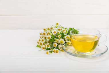 Arka planda taze papatya çiçekleri olan bitki çayı. Sakinleştirici ve rahatlatıcı bir içecek. Dokunulmazlık. Bir fincan sıcak papatya çayı. Çay içme konsepti. Çay seremonisi. Metin için yer, kopyalama alanı.