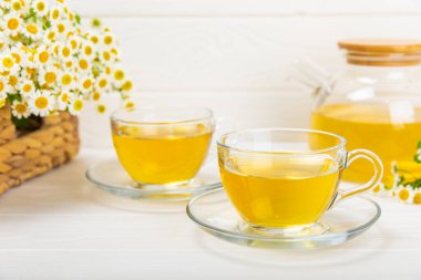 Arka planda taze papatya çiçekleri olan bitki çayı. Sakinleştirici ve rahatlatıcı bir içecek. Dokunulmazlık. Bir fincan sıcak papatya çayı. Çay içme konsepti. Çay seremonisi. Metin için yer, kopyalama alanı.