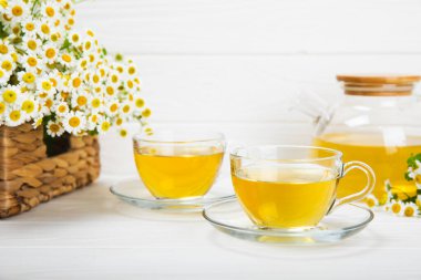 Arka planda taze papatya çiçekleri olan bitki çayı. Sakinleştirici ve rahatlatıcı bir içecek. Dokunulmazlık. Bir fincan sıcak papatya çayı. Çay içme konsepti. Çay seremonisi. Metin için yer, kopyalama alanı.