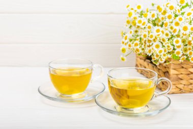 Arka planda taze papatya çiçekleri olan bitki çayı. Sakinleştirici ve rahatlatıcı bir içecek. Dokunulmazlık. Bir fincan sıcak papatya çayı. Çay içme konsepti. Çay seremonisi. Metin için yer, kopyalama alanı.