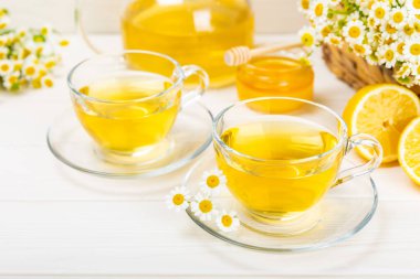 Arka planda taze papatya çiçekleri olan bitki çayı. Sakinleştirici ve rahatlatıcı bir içecek. Dokunulmazlık. Bir fincan sıcak papatya çayı. Çay içme konsepti. Çay seremonisi. Metin için yer, kopyalama alanı.