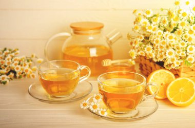 Arka planda taze papatya çiçekleri olan bitki çayı. Sakinleştirici ve rahatlatıcı bir içecek. Dokunulmazlık. Bir fincan sıcak papatya çayı. Çay içme konsepti. Çay seremonisi. Metin için yer, kopyalama alanı.