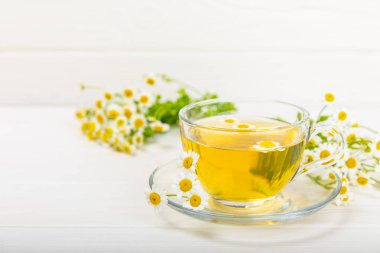 Arka planda taze papatya çiçekleri olan bitki çayı. Sakinleştirici ve rahatlatıcı bir içecek. Dokunulmazlık. Bir fincan sıcak papatya çayı. Çay içme konsepti. Çay seremonisi. Metin için yer, kopyalama alanı.