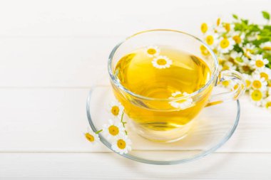 Arka planda taze papatya çiçekleri olan bitki çayı. Sakinleştirici ve rahatlatıcı bir içecek. Dokunulmazlık. Bir fincan sıcak papatya çayı. Çay içme konsepti. Çay seremonisi. Metin için yer, kopyalama alanı.