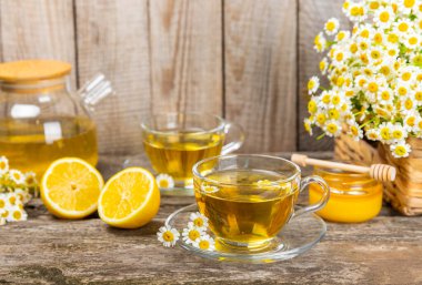 Arka planda taze papatya çiçekleri olan bitki çayı. Sakinleştirici ve rahatlatıcı bir içecek. Dokunulmazlık. Bir fincan sıcak papatya çayı. Çay içme konsepti. Çay seremonisi. Metin için yer, kopyalama alanı.