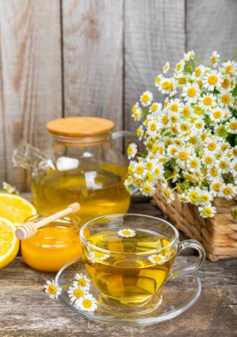 Arka planda taze papatya çiçekleri olan bitki çayı. Sakinleştirici ve rahatlatıcı bir içecek. Dokunulmazlık. Bir fincan sıcak papatya çayı. Çay içme konsepti. Çay seremonisi. Metin için yer, kopyalama alanı.