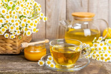 Arka planda taze papatya çiçekleri olan bitki çayı. Sakinleştirici ve rahatlatıcı bir içecek. Dokunulmazlık. Bir fincan sıcak papatya çayı. Çay içme konsepti. Çay seremonisi. Metin için yer, kopyalama alanı.