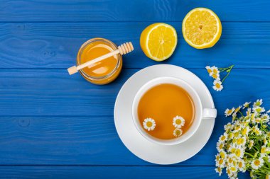 Arka planda taze papatya çiçekleri olan bitki çayı. Sakinleştirici ve rahatlatıcı bir içecek. Dokunulmazlık. Bir fincan sıcak papatya çayı. Çay içme konsepti. Çay seremonisi. Metin için yer, kopyalama alanı.