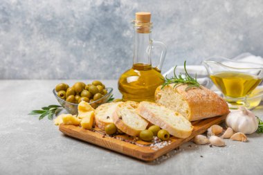 Ciabatta ve zeytin. Otlu taze İtalyan ciabatta ekmeği, zeytinyağı, parmesan ve pesto sosu, ahşap arka planda zeytin, üst manzara, kopyalama alanı. Mesaj için yer. Boşluğu kopyala.