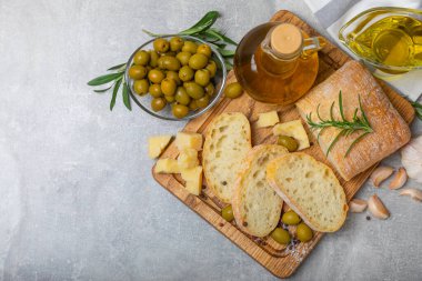 Ciabatta ve zeytin. Otlu taze İtalyan ciabatta ekmeği, zeytinyağı, parmesan ve pesto sosu, ahşap arka planda zeytin, üst manzara, kopyalama alanı. Mesaj için yer. Boşluğu kopyala.