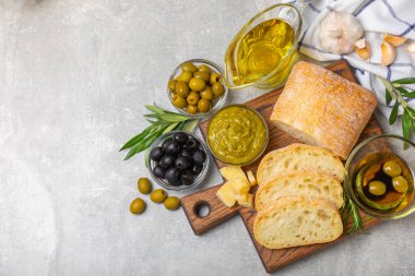 Ciabatta ve zeytin. Otlu taze İtalyan ciabatta ekmeği, zeytinyağı, parmesan ve pesto sosu, ahşap arka planda zeytin, üst manzara, kopyalama alanı. Mesaj için yer. Boşluğu kopyala.