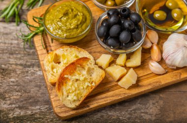 Ciabatta ve zeytin. Otlu taze İtalyan ciabatta ekmeği, zeytinyağı, parmesan ve pesto sosu, ahşap arka planda zeytin, üst manzara, kopyalama alanı. Mesaj için yer. Boşluğu kopyala.