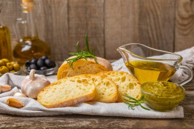 Ciabatta ve zeytin. Otlu taze İtalyan ciabatta ekmeği, zeytinyağı, parmesan ve pesto sosu, ahşap arka planda zeytin, üst manzara, kopyalama alanı. Mesaj için yer. Boşluğu kopyala.