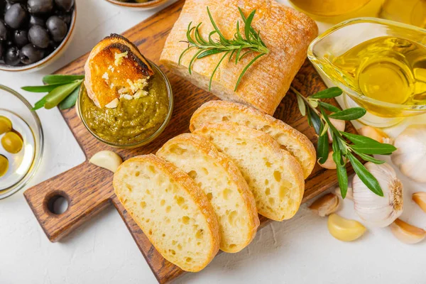 Ciabatta ve zeytin. Otlu taze İtalyan ciabatta ekmeği, zeytinyağı, parmesan ve pesto sosu, ahşap arka planda zeytin, üst manzara, kopyalama alanı. Mesaj için yer. Boşluğu kopyala.