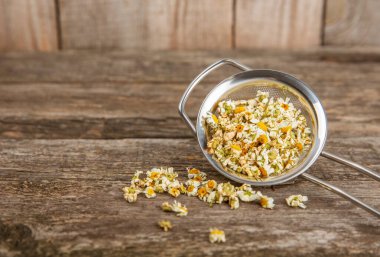 Tahta bir masanın üzerinde papatya çiçekleri. Rahatlatıcı papatya çayı. Bitkisel içecek. Düz plan. Ders için alan. Kopya alanı. Tıbbi önleme ve bağışıklık konsepti. Halk alternatif tıbbı.