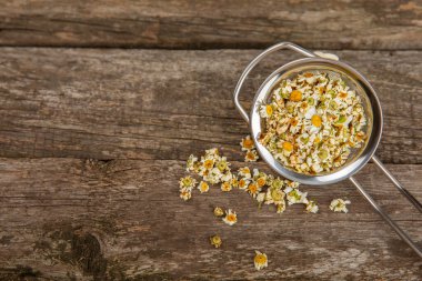 Tahta bir masanın üzerinde papatya çiçekleri. Rahatlatıcı papatya çayı. Bitkisel içecek. Düz plan. Ders için alan. Kopya alanı. Tıbbi önleme ve bağışıklık konsepti. Halk alternatif tıbbı.