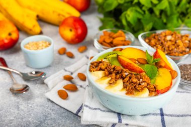 Bir kase granola yoğurt ve dokuma masasında taze böğürtlen. Yoğurt böğürtlen, acai kasesi, spirulina kasesi. Sağlıklı yemek, dengeli kahvaltı. Çilek, yabanmersini, kivi, şeftali, badem ve chia..