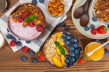 Bir kase granola yoğurt ve dokuma masasında taze böğürtlen. Yoğurt böğürtlen, acai kasesi, spirulina kasesi. Sağlıklı yemek, dengeli kahvaltı. Çilek, yabanmersini, kivi, şeftali, badem ve chia..