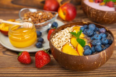 Bir kase granola yoğurt ve dokuma masasında taze böğürtlen. Yoğurt böğürtlen, acai kasesi, spirulina kasesi. Sağlıklı yemek, dengeli kahvaltı. Çilek, yabanmersini, kivi, şeftali, badem ve chia..