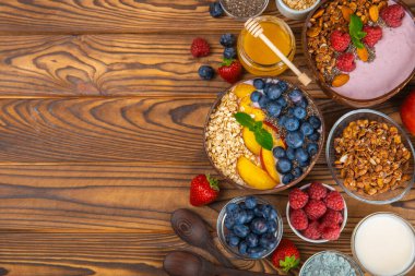 Bir kase granola yoğurt ve dokuma masasında taze böğürtlen. Yoğurt böğürtlen, acai kasesi, spirulina kasesi. Sağlıklı yemek, dengeli kahvaltı. Çilek, yabanmersini, kivi, şeftali, badem ve chia..