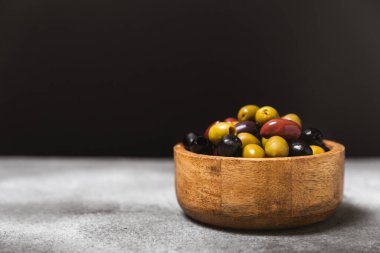 Mermer zemin üzerinde yeşil, kırmızı ve siyah zeytin seti. Kâselerde çeşitli zeytin ve taze zeytin yaprakları. Vejetaryen. Zeytin meyveleri. Mesaj için yer. Boşluğu kopyala.