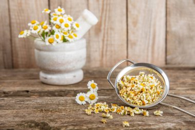 Tahta bir masanın üzerinde papatya çiçekleri. Rahatlatıcı papatya çayı. Bitkisel içecek. Düz plan. Ders için alan. Kopya alanı. Tıbbi önleme ve bağışıklık konsepti. Halk alternatif tıbbı.