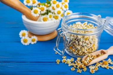 Tahta bir masanın üzerinde papatya çiçekleri. Rahatlatıcı papatya çayı. Bitkisel içecek. Düz plan. Ders için alan. Kopya alanı. Tıbbi önleme ve bağışıklık konsepti. Halk alternatif tıbbı.