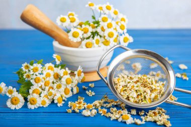 Tahta bir masanın üzerinde papatya çiçekleri. Rahatlatıcı papatya çayı. Bitkisel içecek. Düz plan. Ders için alan. Kopya alanı. Tıbbi önleme ve bağışıklık konsepti. Halk alternatif tıbbı.