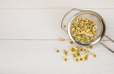 Tahta bir masanın üzerinde papatya çiçekleri. Rahatlatıcı papatya çayı. Bitkisel içecek. Düz plan. Ders için alan. Kopya alanı. Tıbbi önleme ve bağışıklık konsepti. Halk alternatif tıbbı.