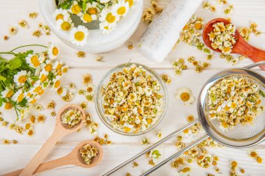 Tahta bir masanın üzerinde papatya çiçekleri. Rahatlatıcı papatya çayı. Bitkisel içecek. Düz plan. Ders için alan. Kopya alanı. Tıbbi önleme ve bağışıklık konsepti. Halk alternatif tıbbı.