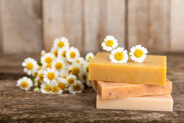 Ahşap bir masada papatya çiçekli doğal ev yapımı sabun. Doğal bitkisel yağlarla nemlendirici sabun yakın plan. Spa ve güzellik konsepti. Mesaj için yer. Uzayı kopyala. Fletley