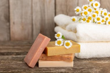 Ahşap bir masada papatya çiçekli doğal ev yapımı sabun. Doğal bitkisel yağlarla nemlendirici sabun yakın plan. Spa ve güzellik konsepti. Mesaj için yer. Uzayı kopyala. Fletley