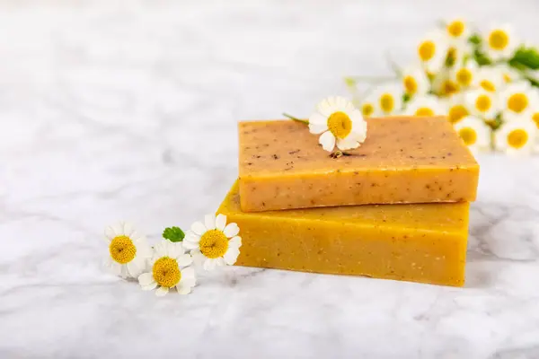 Natural homemade soap with chamomile flowers on a wooden table. Close-up of moisturizing soap with natural herbal oils. Spa and beauty concept. Place for text. Copy space.Fletley