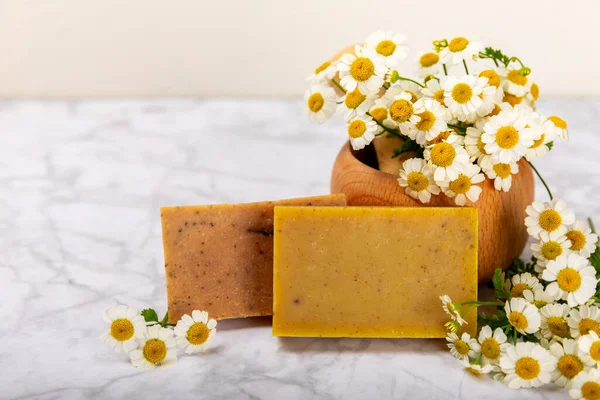 Natural homemade soap with chamomile flowers on a wooden table. Close-up of moisturizing soap with natural herbal oils. Spa and beauty concept. Place for text. Copy space.Fletley