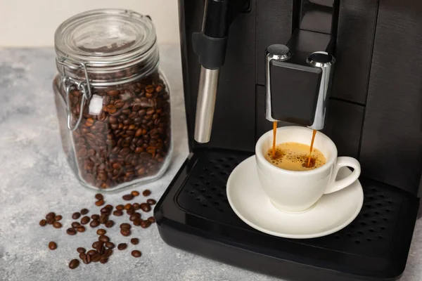 Modern coffee machine with a cup on the kitchen table. Coffee house. Modern espresso coffee machine with a cup in the kitchen. Preparation of a fragrant hot drink. Place for text.Copy space.