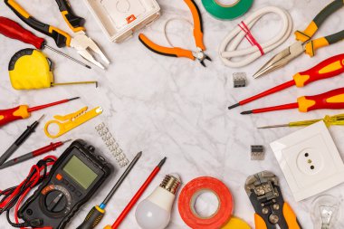 Elektrik teçhizatı arka planda. Multimetre, inşaat bandı, elektrik bandı, tornavida, pense, otomatik yalıtım striptizcisi, soket ve LED lamba..