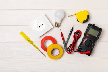 Elektrik teçhizatı arka planda. Multimetre, inşaat bandı, elektrik bandı, tornavida, pense, otomatik yalıtım striptizcisi, soket ve LED lamba..