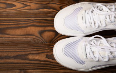 Kahverengi arka planda beyaz ayakkabılar. Moda. UNISEX. Spor ayakkabıları aktif bir yaşam tarzı için spor ayakkabılarıdır. Ürün fotoğrafı ve havalanma konsepti. Sokak tarzı. Uzayı kopyala Metin için yer.