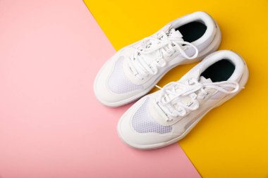 Pembe arka planda beyaz ayakkabılar. Moda. UNISEX. Spor ayakkabıları aktif bir yaşam tarzı için spor ayakkabılarıdır. Ürün fotoğrafı ve havalanma konsepti. Sokak tarzı. Uzayı kopyala Metin için yer.