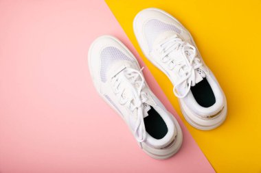 Pembe arka planda beyaz ayakkabılar. Moda. UNISEX. Spor ayakkabıları aktif bir yaşam tarzı için spor ayakkabılarıdır. Ürün fotoğrafı ve havalanma konsepti. Sokak tarzı. Uzayı kopyala Metin için yer.
