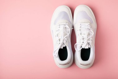 Pembe arka planda beyaz ayakkabılar. Moda. UNISEX. Spor ayakkabıları aktif bir yaşam tarzı için spor ayakkabılarıdır. Ürün fotoğrafı ve havalanma konsepti. Sokak tarzı. Uzayı kopyala Metin için yer.