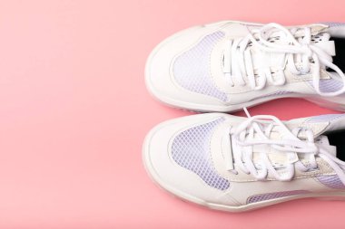 Pembe arka planda beyaz ayakkabılar. Moda. UNISEX. Spor ayakkabıları aktif bir yaşam tarzı için spor ayakkabılarıdır. Ürün fotoğrafı ve havalanma konsepti. Sokak tarzı. Uzayı kopyala Metin için yer.