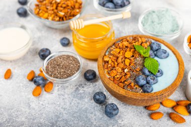 Bir kase granola yoğurt ve dokuma masasında taze böğürtlen. Yoğurt böğürtlen, acai kasesi, spirulina kasesi. Sağlıklı yemek, dengeli kahvaltı. Çilek, yabanmersini, kivi, şeftali, badem ve chia..